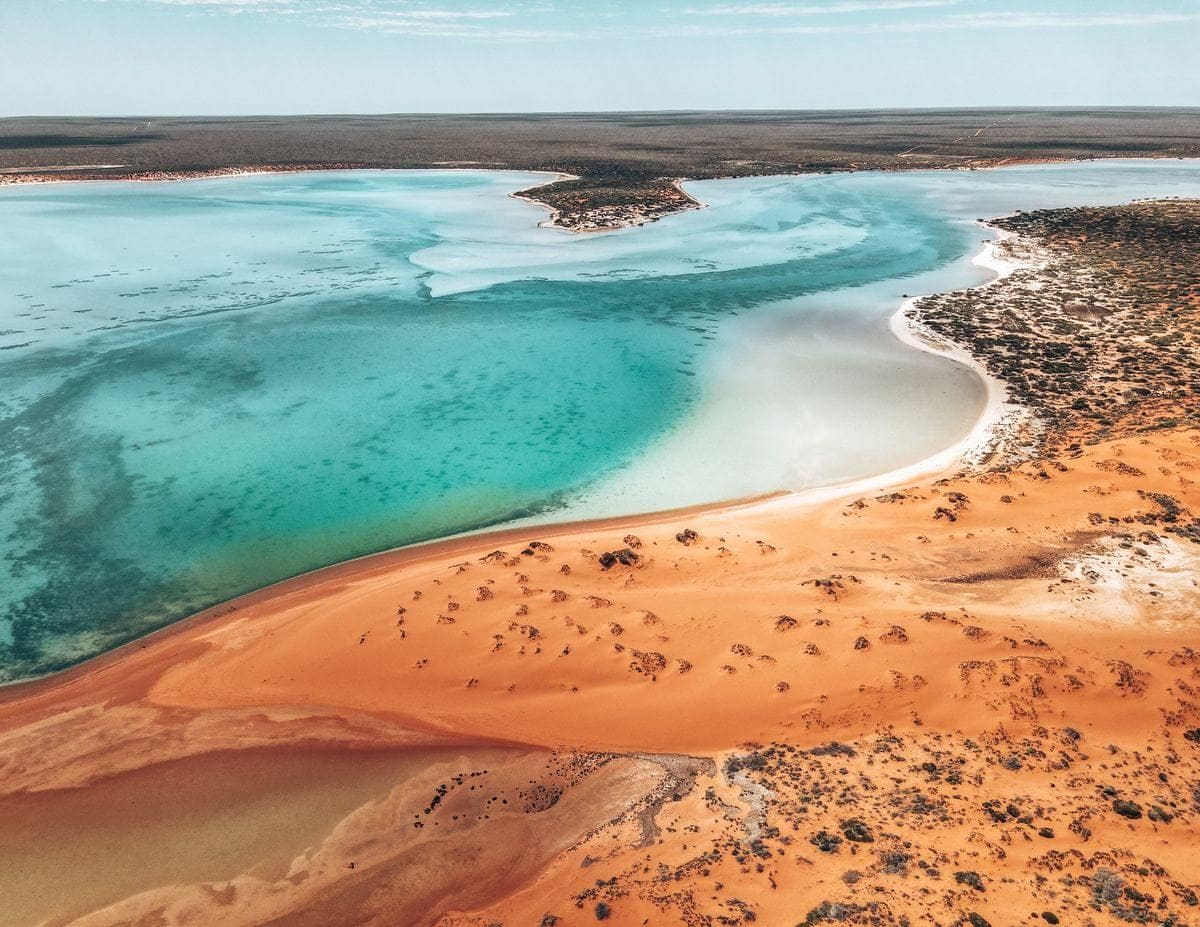 Turquoise coastal waters meeting white sand and red earth in Western Australia